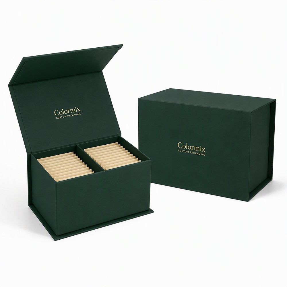 Dark green flip-lid tea box open to show two compartments of wrapped tea sachets