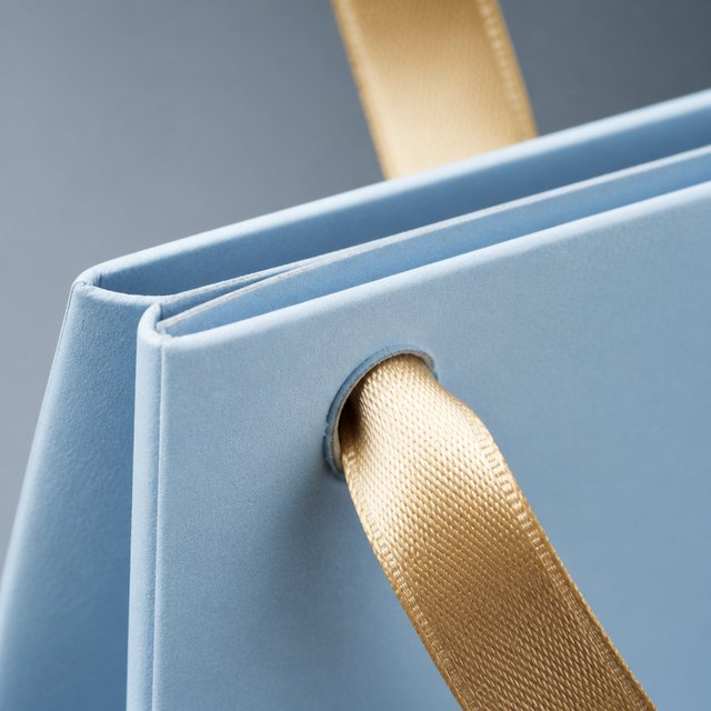 Close-up of a paper bag top hem with a ribbon handle set through a reinforced hole